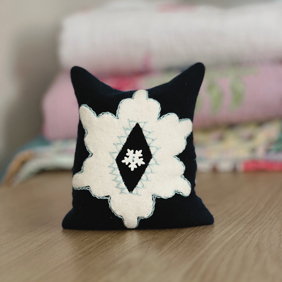 photo of a pincushion with a wool star appliqué with embroidery stitches