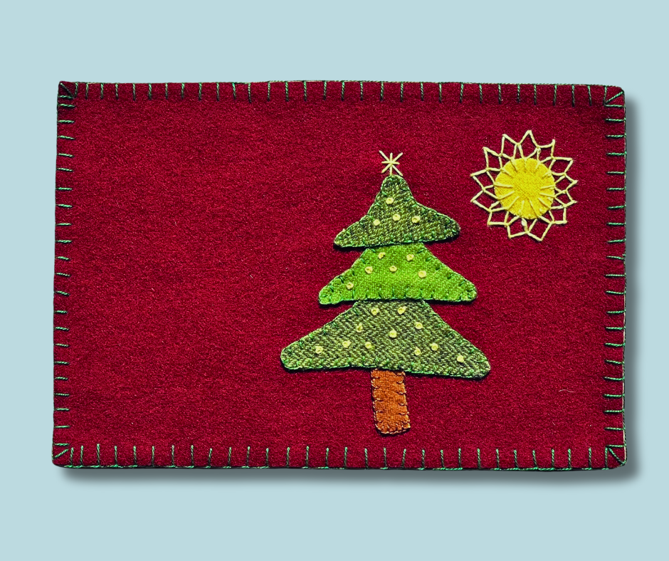 Photo of a wool appliqué mug rug with a green tree and hand embroidered lights and a big star.