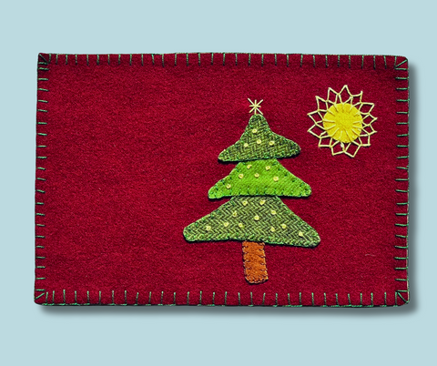 Photo of a 6 x 9" wool mug rug with a christmas tree appliqué and a large start with hand embroidery