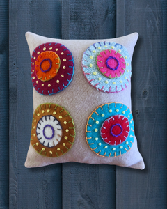 Photo of a wool penny pincushion with four wool pennies embellished with perle cotton embroidery stitches.