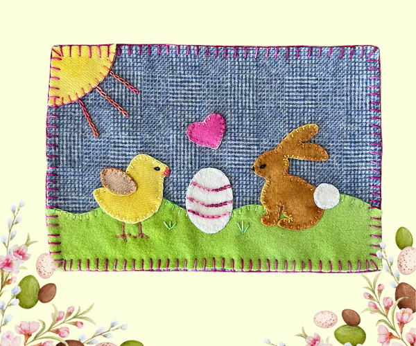 Photo of a wool appliqué mug rug featuring a yellow chick and a brown bunny with an easter egg between them and perle cotton embellishements.