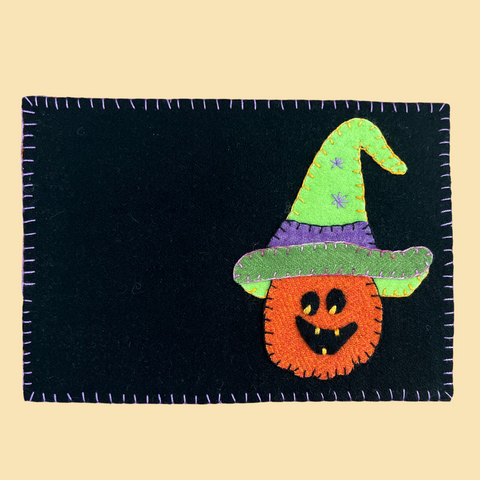 photo of a 9" x 6" hand sewn mug rug with a pumpkin in a wizard hat