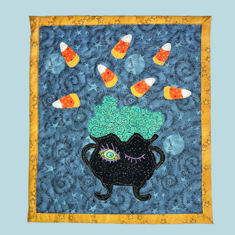 Photo of a quilted table mat with applique cauldron and candy corn free pattern and video tutorial