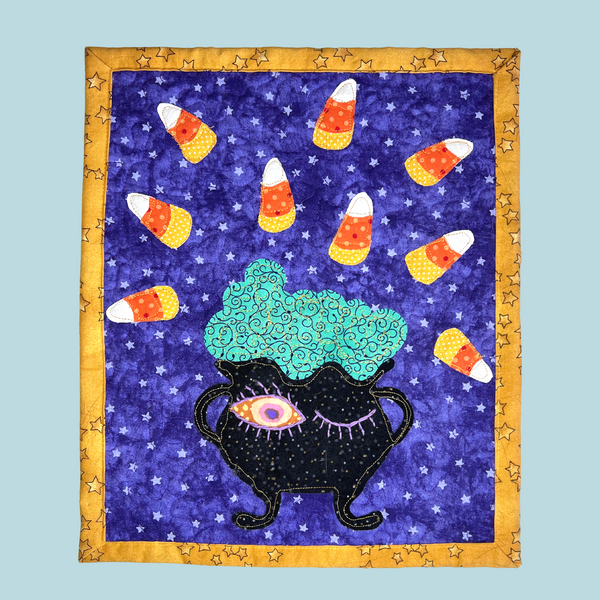 Photo of a quilted table mat with applique cauldron and candy corn free pattern and video tutorial