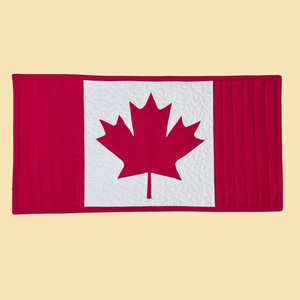 A photo of a quilted table runner with straight quilting and free motion quilting in the shape of a Canadian Flag