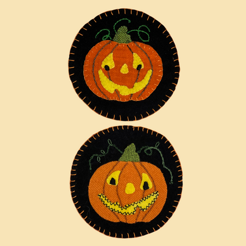 photo of two round wool applique pumpkin coasters