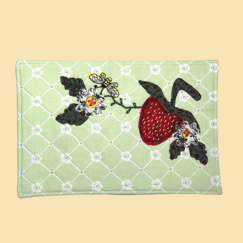 photo of a quilted cotton mug rug with a strawberry applique and bee motif fabric